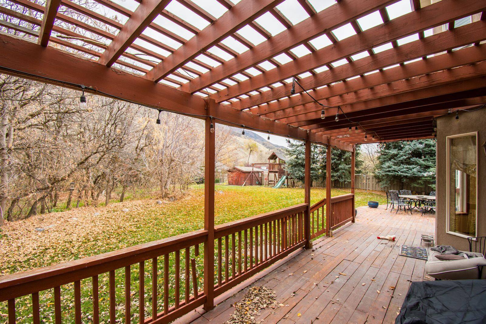 A wooden deck stained a warm red-brown under a pergola
