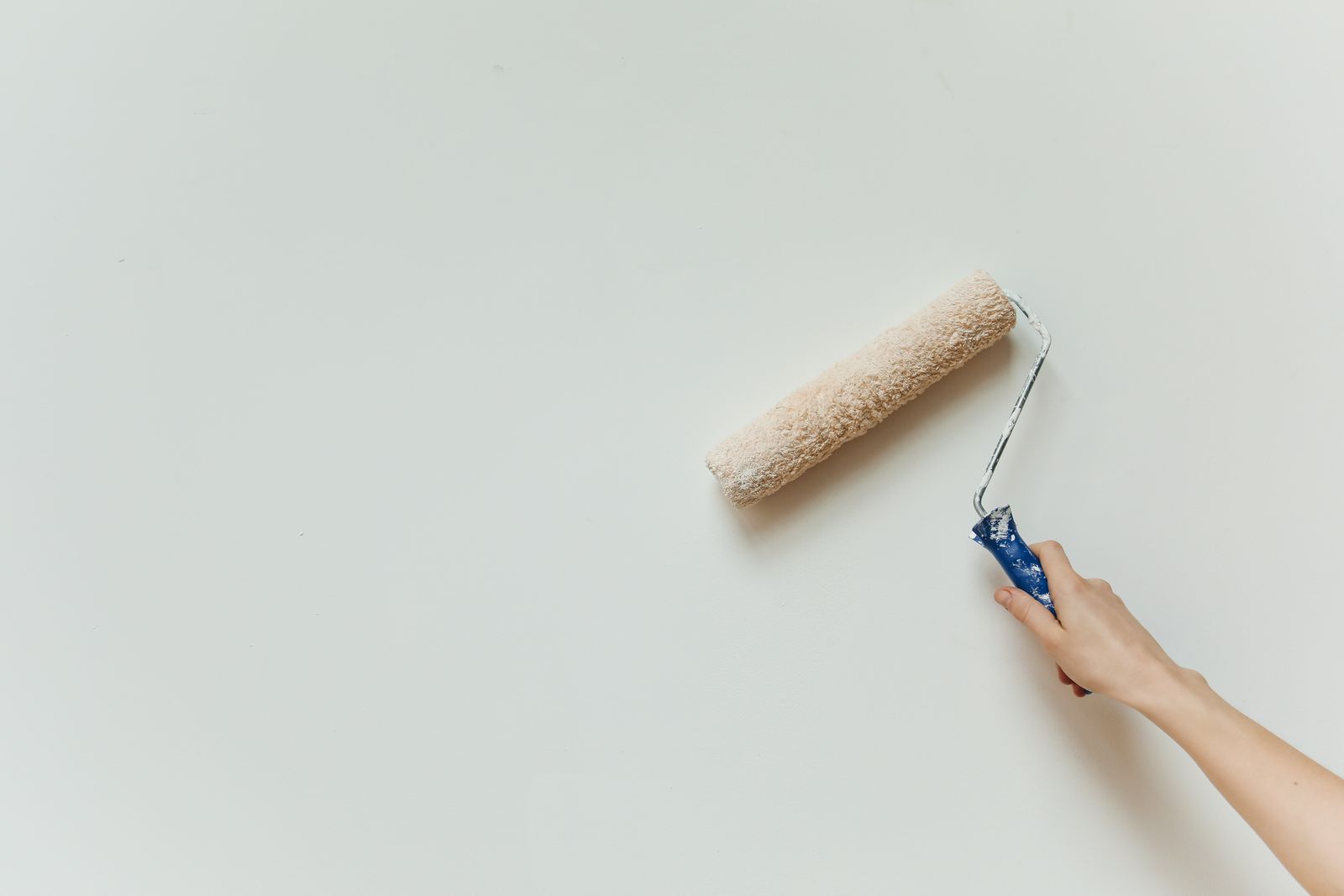 A roller laying fresh white paint on a wall